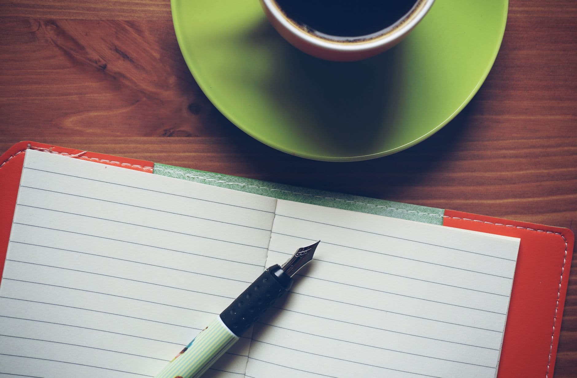 Carnet ouvert sur une table en bois avec un stylo posé dessus, lumière naturelle du matin