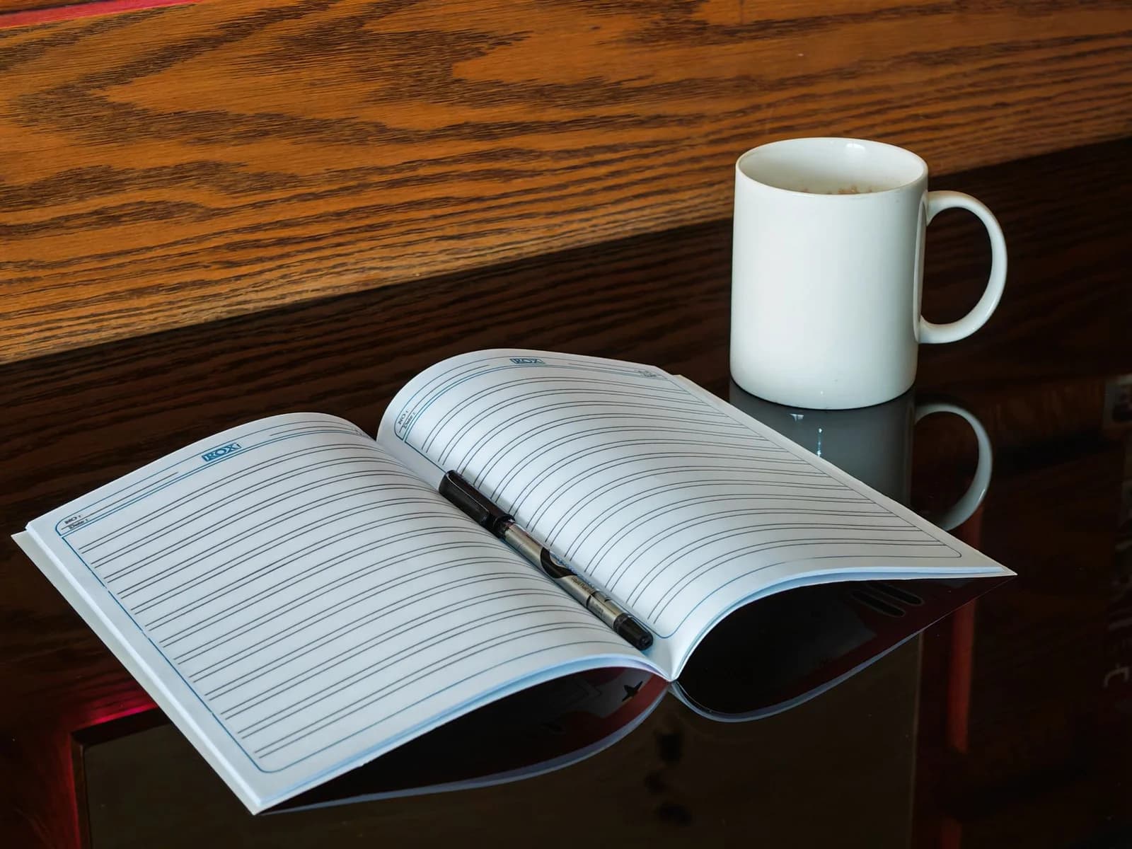 Carnet de notes ouvert sur un bureau en bois clair avec un café, lumière naturelle matinale